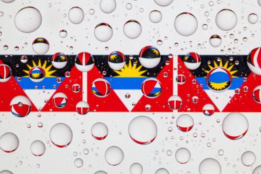 Antigua ve Barbuda bayrakları yağmur damlaları ile kaplı bir cam arkasında.