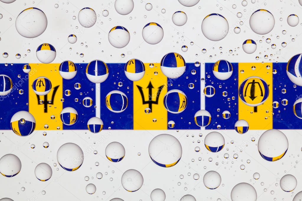 Flags  of Barbados behind a glass covered with raindrops.