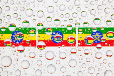 Yağmur damlaları ile kaplı bir cam arkasında Etiyopya bayrakları.