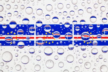 Yağmur damlaları ile kaplı bir cam arkasında Cape Verde bayrakları.