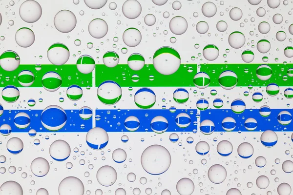 塞拉利昂国旗在一个覆盖着雨滴的玻璃后面 — 图库照片