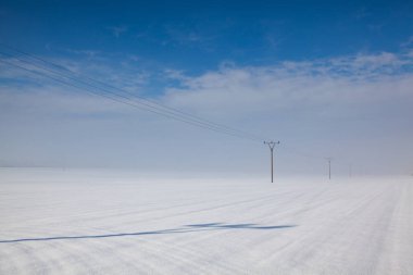 Güç hatları olan kış manzarası. Sütunlar karla kaplı bir tarla..