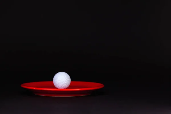 Röd tallrik och golfboll på svarta bordet — Stockfoto
