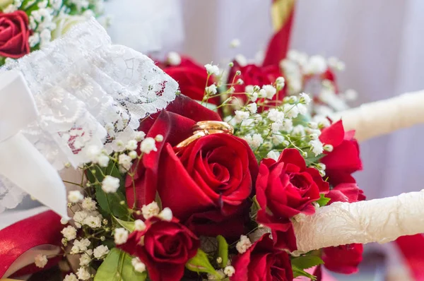 Wedding rings on a bouquet of red roses. Wedding Candles. Bouquet of the bride. Garter of the bride