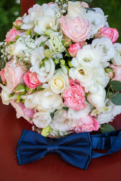 花嫁の結婚式の花束白とピンクの花 赤い箱の金の結婚指輪の隣に青い弓のネクタイ 白とピンクのバラ — ストック写真
