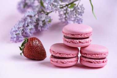 Seçici odak üç pembe macaroons ve pembe bir arka plan üzerinde çilek