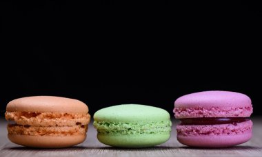 Pembe, yeşil ve turuncu macaroons ahşap masa üzerinde. Rustik tarzı