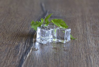 Buz küpleri ve ısırgan yaprakları ahşap arka plan üzerinde 