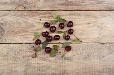Olgun kiraz ve vişne yapraklarda ahşap bir masa. Üstten görünüm