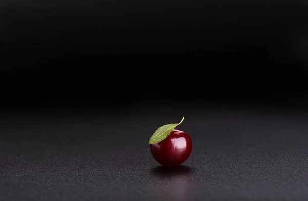 Ripe sweet cherry with cherry leaf isolated on black background close up