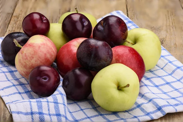 Fresh apples and plums on wooden table