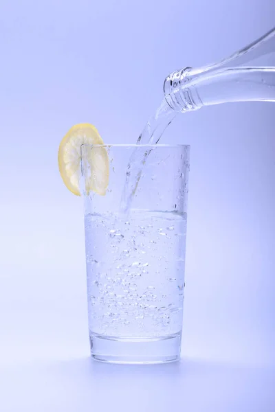 Air Tawar Dingin Mengalir Gelas Dengan Lemon Dari Botol — Stok Foto