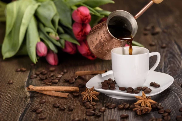 Menuang kopi ke dalam cangkir putih dengan latar belakang tulip menutup — Stok Foto