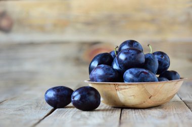 Ahşap arka plan üzerinde kase taze erik. Kopya alanı