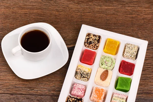 Black coffee and varied Turkish delight on a wooden table — Stock Photo, Image