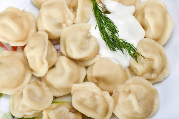 Hot dumplings with sour cream and dill. Traditional Russian dish — Stock Photo, Image