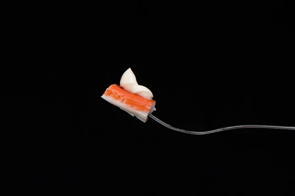 Uma fatia de paus de caranguejo com maionese em um garfo isolado em bla — Fotografia de Stock