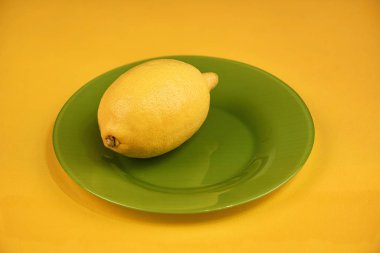 Bütün limon sarı bir arka plan üzerinde yeşil bir tabakta. Kopya alanı