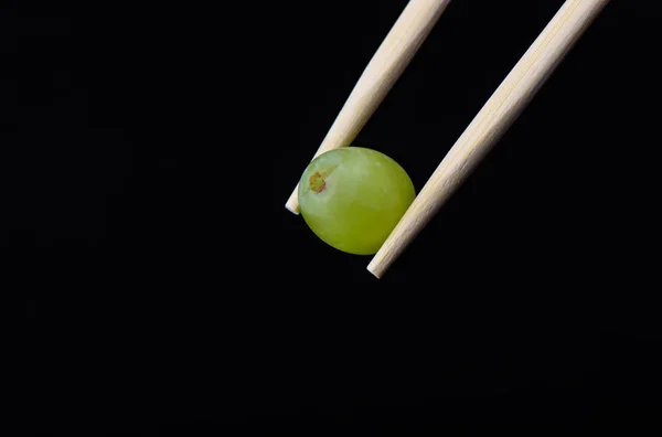葡萄浆果在筷子查出在黑色背景. — 图库照片