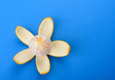 Mavi arka planda izole turuncu soyulmuş. Yaprakları olarak turuncu kabuğu