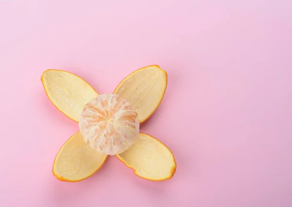 Geschälte Orange isoliert auf rosa Hintergrund. Orangenschale als Blütenblätter — Stockfoto