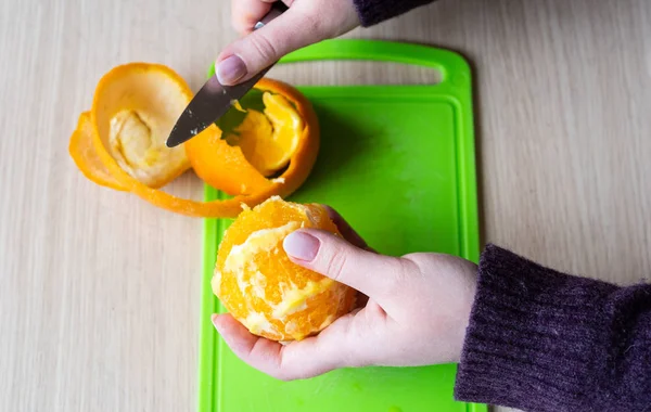 Mädchen putzt die Orange mit einem Messer. gesunde Ernährung. — Stockfoto