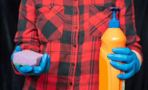 Kitchen sponge and cleaning agent in the hands of the girl. Girl\'s hands in a hygienic gloves.