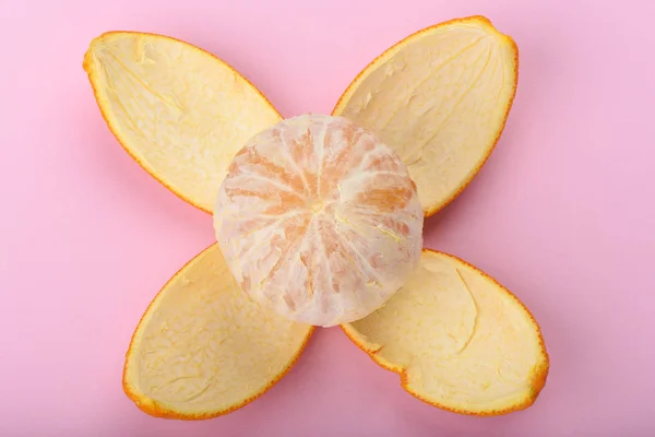Peeled orange isolated on pink background. Orange peel as petals