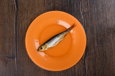 Ahşap bir arka plan üzerinde turuncu bir plaka üzerinde soğuk füme Baltık Ringa balığı. Füme Baltık Ringa balığı altın kahverengi kadar füme.