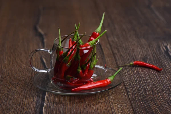 Pods of red hot pepper in a glass mug on a wooden background. Pepper pod on wooden table — Stock Photo, Image
