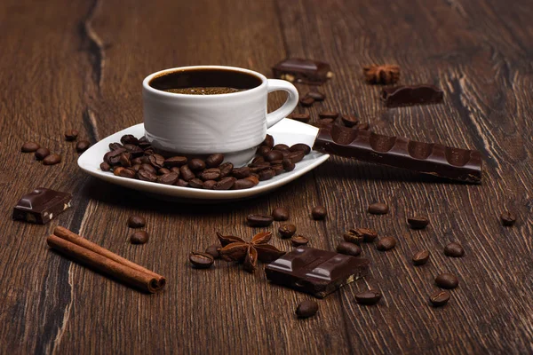 Secangkir dengan kopi panas dan coklat, kayu manis, bintang adas di atas meja kayu . — Stok Foto