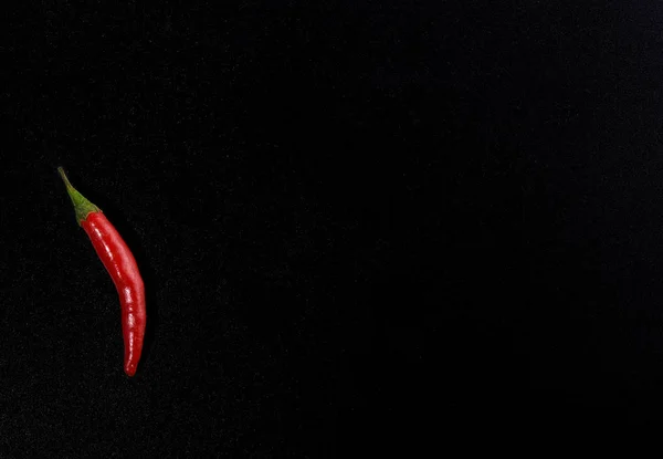 Pod of red hot pepper isolated on black color background.