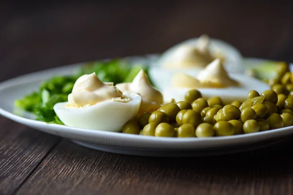 Zachte focus. Gekookte eieren onder mayonaise met groene erwten en groene uien. Een traditioneel Russisch gerecht. — Stockfoto