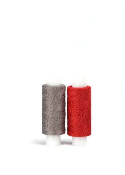 Baumwollrote und graue Fäden auf dem Kunststoffärmel für die Nähmaschine. — Stockfoto