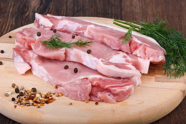 Pork steaks on a wooden cutting board with dill and spices. Raw pork meat for steaks. — Stock Photo, Image