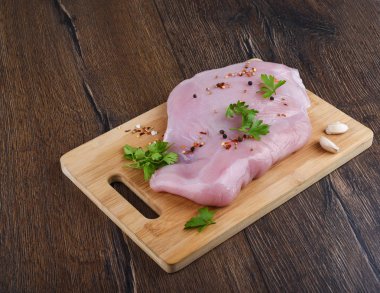 Ham hindi fileto ile maydanoz ve baharatlar ile ahşap bir kesme tahtası ve ahşap masa.. Rustik tarzı.