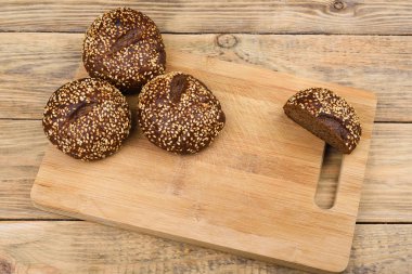 Kesme tahtası ve ahşap bir masa üzerinde susam ile Malt ekmek. Dilimlenmiş ekmek. 