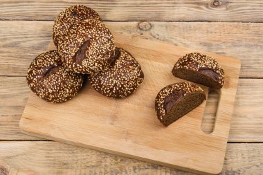 Kesme tahtası ve ahşap bir masa üzerinde susam ile Malt ekmek. Dilimlenmiş ekmek. 