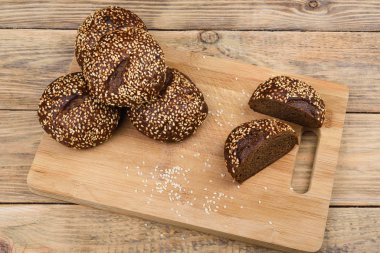 Kesme tahtası ve ahşap bir masa üzerinde susam ile Malt ekmek. Dilimlenmiş ekmek. 