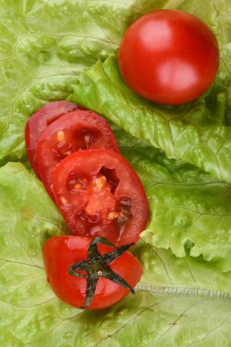 Olgun bütün domates ve taze marul yaprakları üzerinde dilimler halinde kesilmiş.