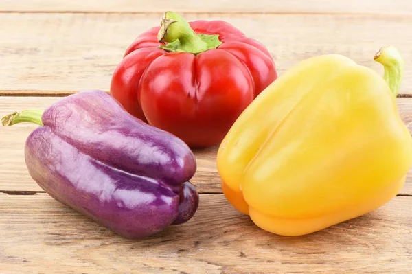 Multi-colored pods of sweet peppers on a wooden table. — Stock Photo, Image