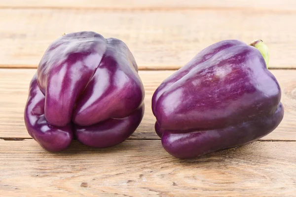 Two fresh purple bell peppers on a wooden table. — Stock Photo, Image