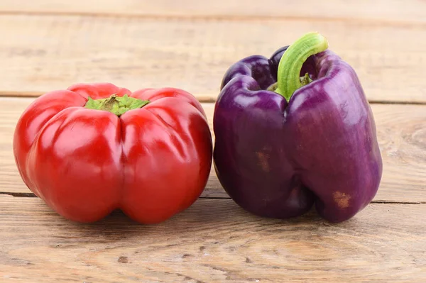 Red and purple fresh bell peppers on a wooden table. — Stock Photo, Image