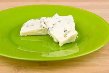 Yeşil bir tabakta lezzetli mavi kalıp peynir dilimleri.