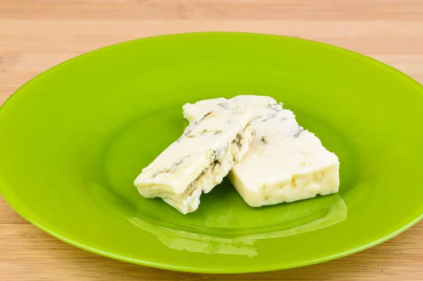 Trozos de queso azul en un plato verde . — Foto de Stock