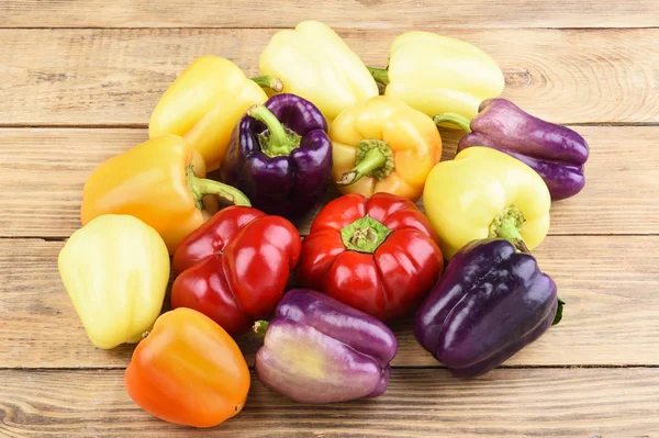 Colorful ripe bell peppers on a wooden table.