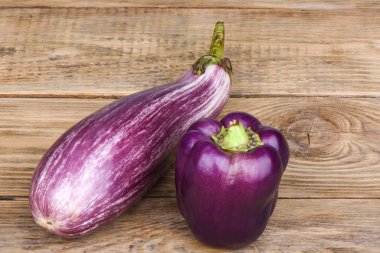 Ahşap bir masada patlıcan grafiti ve mor biber.