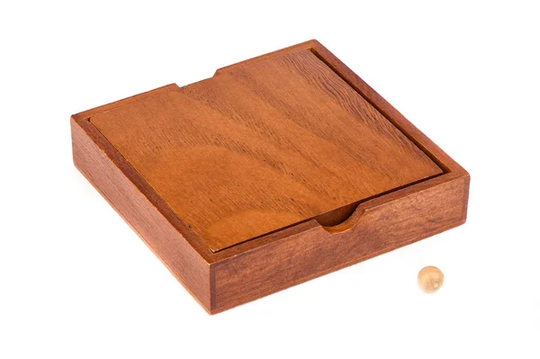 Wooden box and ball for playing Madagascar checkers over white.