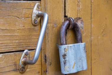 Eski bir asma kilit ahşap bir kapıyı kilitler.