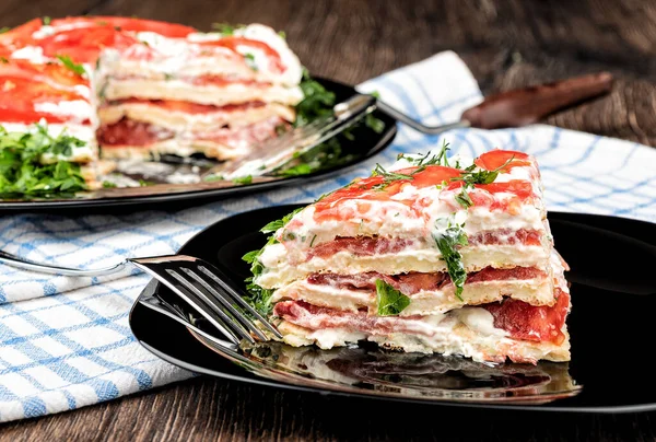 Slice of vegetarian pie made from squash pancakes, cream and tomatoes on a black plate. — Stock Photo, Image